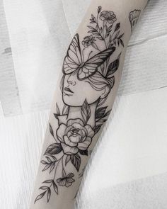 a woman's arm with flowers and butterflies on it, in black and white