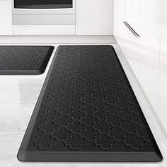 two black bath mats sitting on top of a white floor in front of an oven