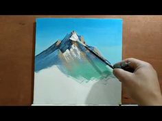 someone is painting a mountain on a canvas