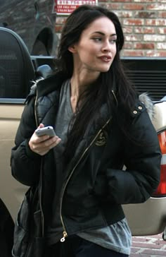 a woman walking down the street while looking at her cell phone