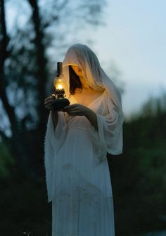 a woman dressed in white holding a lit candle