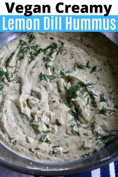 a bowl filled with creamy lemon dill hummus on top of a blue and white towel