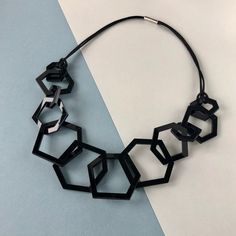 A stylish black geometric mid-length chunky acrylic necklace. A stylish, modern black necklace for the jewellery lover who likes simple design and colourful jewellery.  My necklaces are light and easy to wear and will give your favourite outfit an instant pop of colour. Designed using twelve laser cut perpsex shapes linked together the necklace is 24 inches long with a drop of 12 inches. There are 4 large, 4 medium and 4 small shapes measuring 2, 1.5 and 1 inch wide each. Finished with silky bla Black Geometric Jewelry, Bold Black Necklace For Gifts, Bold Black Necklace For Gift, Trendy Black Geometric Jewelry, Modern Black Geometric Necklace, Geometric Black Necklace For Gift, Black Geometric Necklace For Gift, Colourful Jewellery, Acrylic Necklace