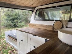 the interior of a camper with wood flooring and white cabinets in front of it