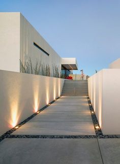 an outdoor walkway with lights on the sides and steps leading up to a house in the background