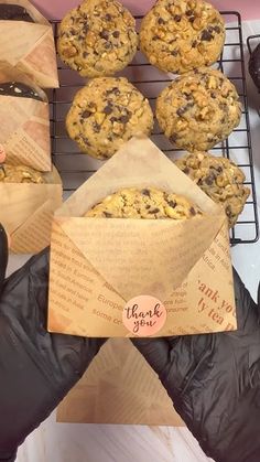 chocolate chip cookies and doughnuts sitting on a cooling rack with paper wrappers