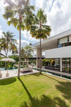 a house with palm trees in front of it and a swimming pool on the other side