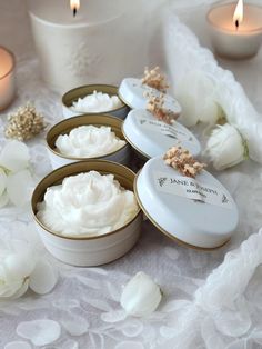 four small white containers filled with whipped cream next to candles and flowers on a table