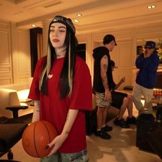 a girl with long hair holding a basketball in front of her face and people behind her