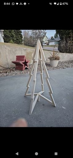 a wooden christmas tree sitting on top of a cement ground