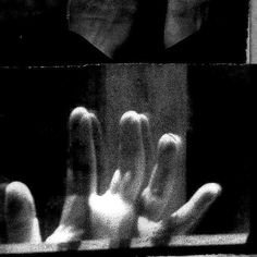 black and white photograph of person's hands in front of a window with their reflection