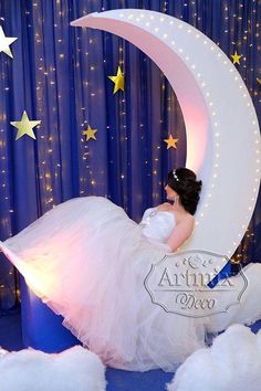 a woman in a white dress sitting on top of a crescent shaped moon with stars