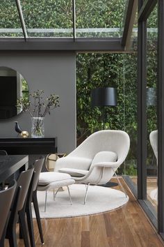 a living room filled with furniture next to a window covered in plants and greenery