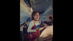 a woman standing on an airplane holding a book