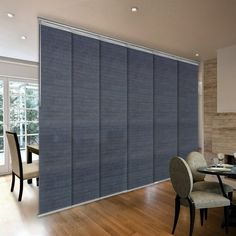 a dining room with blue roller shades in the window and wooden flooring on the walls