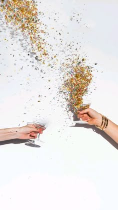 two people holding wine glasses with confetti falling from the top to the bottom