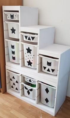 a white shelf filled with lots of bins on top of a hard wood floor