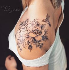 the back of a woman's shoulder with flowers and leaves tattooed on her chest