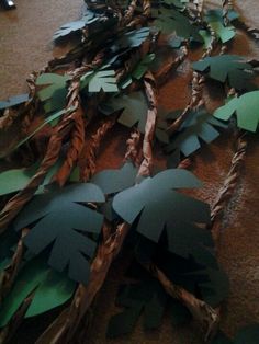 several pieces of paper cut out to look like leaves on the ground with people standing in the background