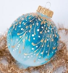 a blue ornament sitting on top of some dry grass and gold foiling