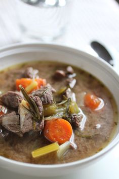 a bowl of soup with meat, carrots and celery on the side