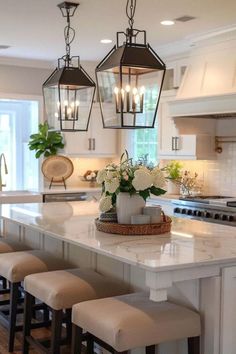 a kitchen island with stools and lights hanging over it