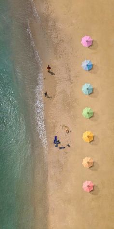 an aerial view of people on the beach with umbrellas in the sand and water