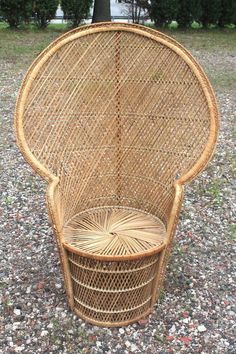 a wicker chair sitting on top of a gravel covered ground next to a tree