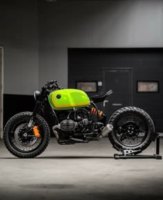 a green motorcycle parked in a garage next to a black door and some lights on