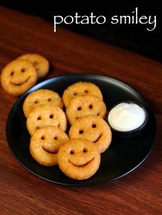 potato smiley crackers on a black plate with ranch dip in the middle and another snack behind it