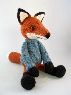 a knitted stuffed fox sitting on top of a white surface