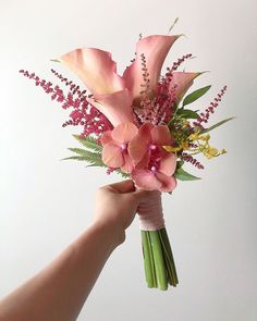 a hand holding a bouquet of pink flowers