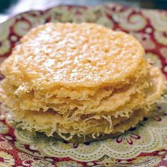 a stack of pancakes sitting on top of a red and white plate with doily