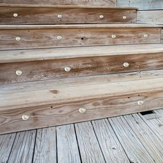 some wooden steps with white knobs and nails on the bottom one is painted light brown