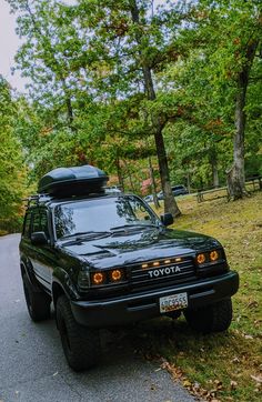 a black toyota pickup truck parked on the side of a road in front of trees