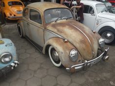 an old rusty car is parked next to other cars