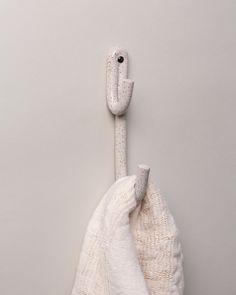 a white towel hanging on the side of a wall next to a hook with an object in it