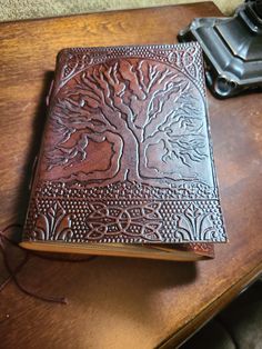 a brown leather journal sitting on top of a wooden table next to a black camera