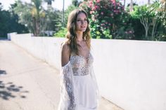 a woman standing on the side of a road wearing a white dress