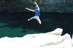 a man jumping into the water from a cliff