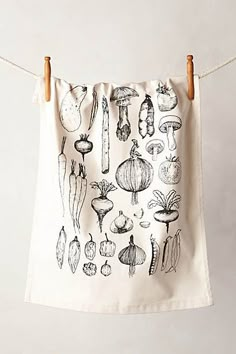 a tea towel hanging on a clothes line with mushrooms and other vegetables drawn on it