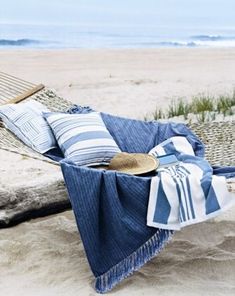 a hammock on the beach with blue and white blankets