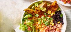 a salad with black beans, corn and lettuce in a white bowl on a table