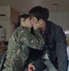 a man and woman kissing while sitting on top of a couch in a living room