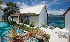 an aerial view of a house with a pool in the foreground and ocean in the background