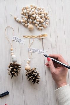 a person is holding a pen and writing on some pinecone tags next to other items