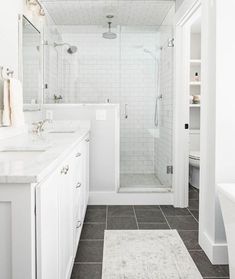 a white bathroom with two sinks and a walk in shower