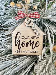 a wooden ornament hanging on a christmas tree with the words our new home