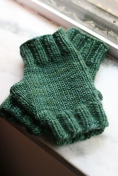 a pair of green knitted mittens sitting on top of a counter next to a window