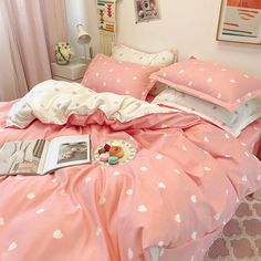 a pink bed with white polka dots on it and a magazine laying on the pillow